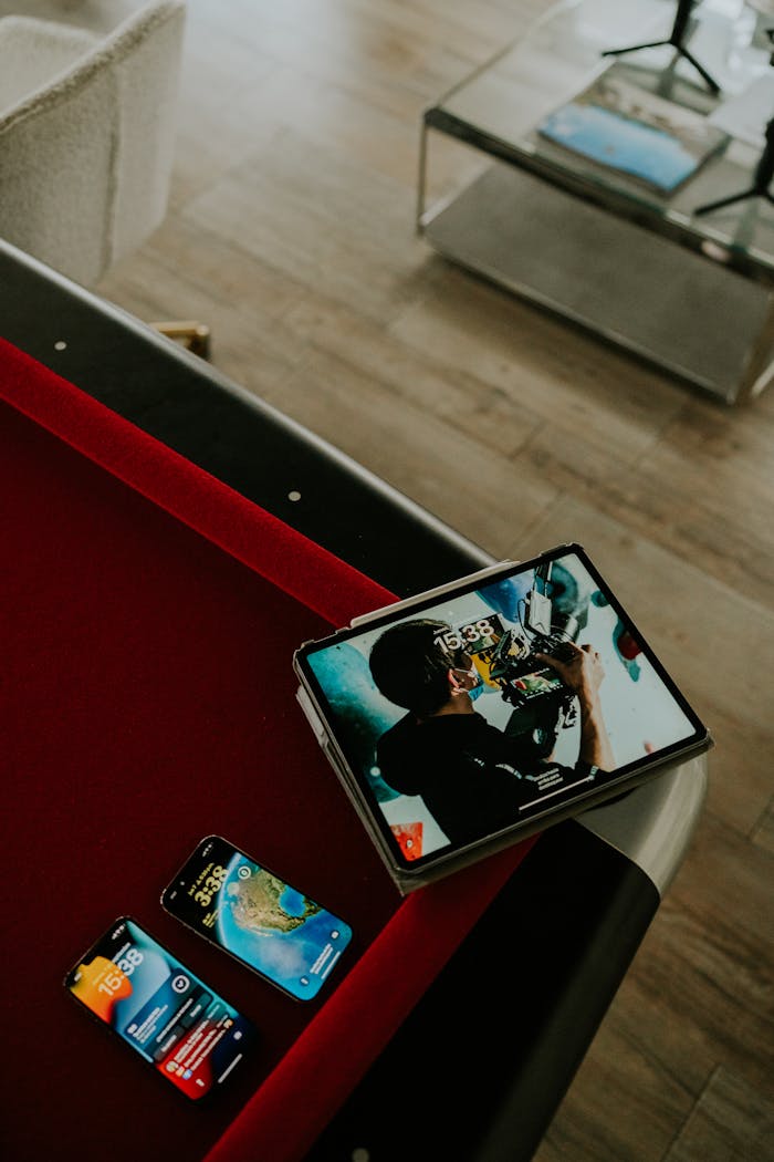 A tablet and smartphones displayed on a pool table in a stylish living room setting.