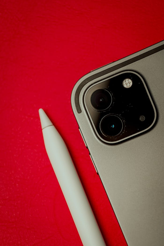Close-up photo of a smartphone and stylus on a red background, highlighting modern technology.